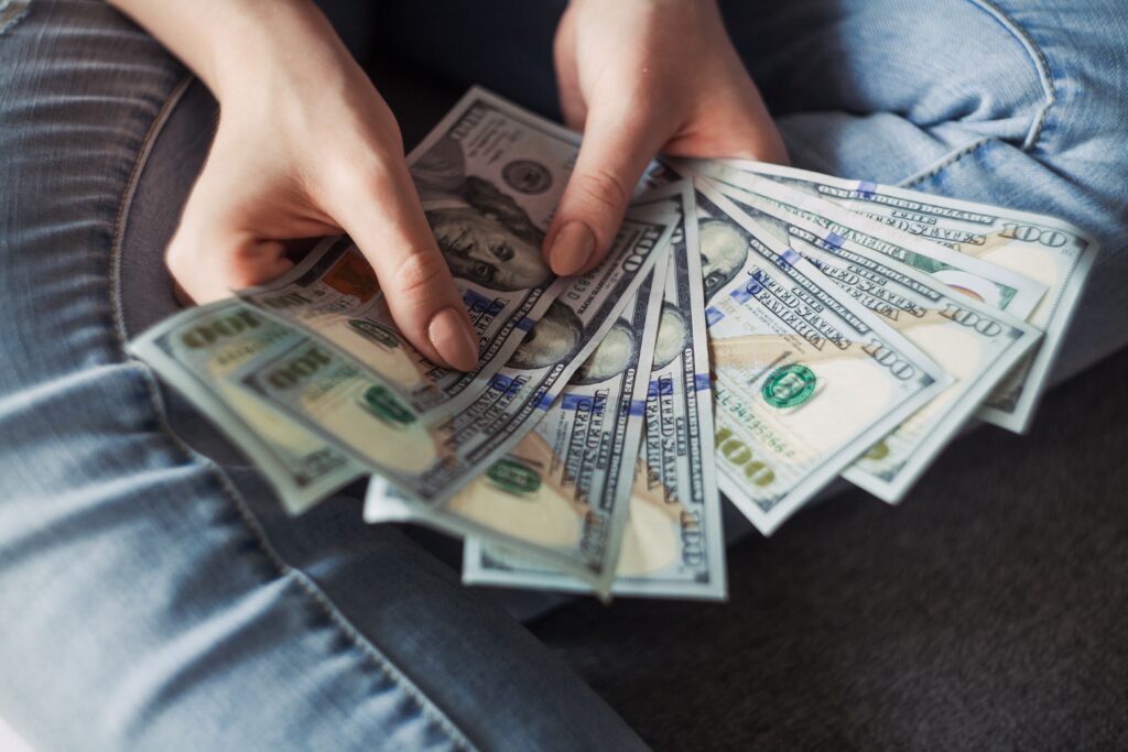 Person holding 100 dollar bills
